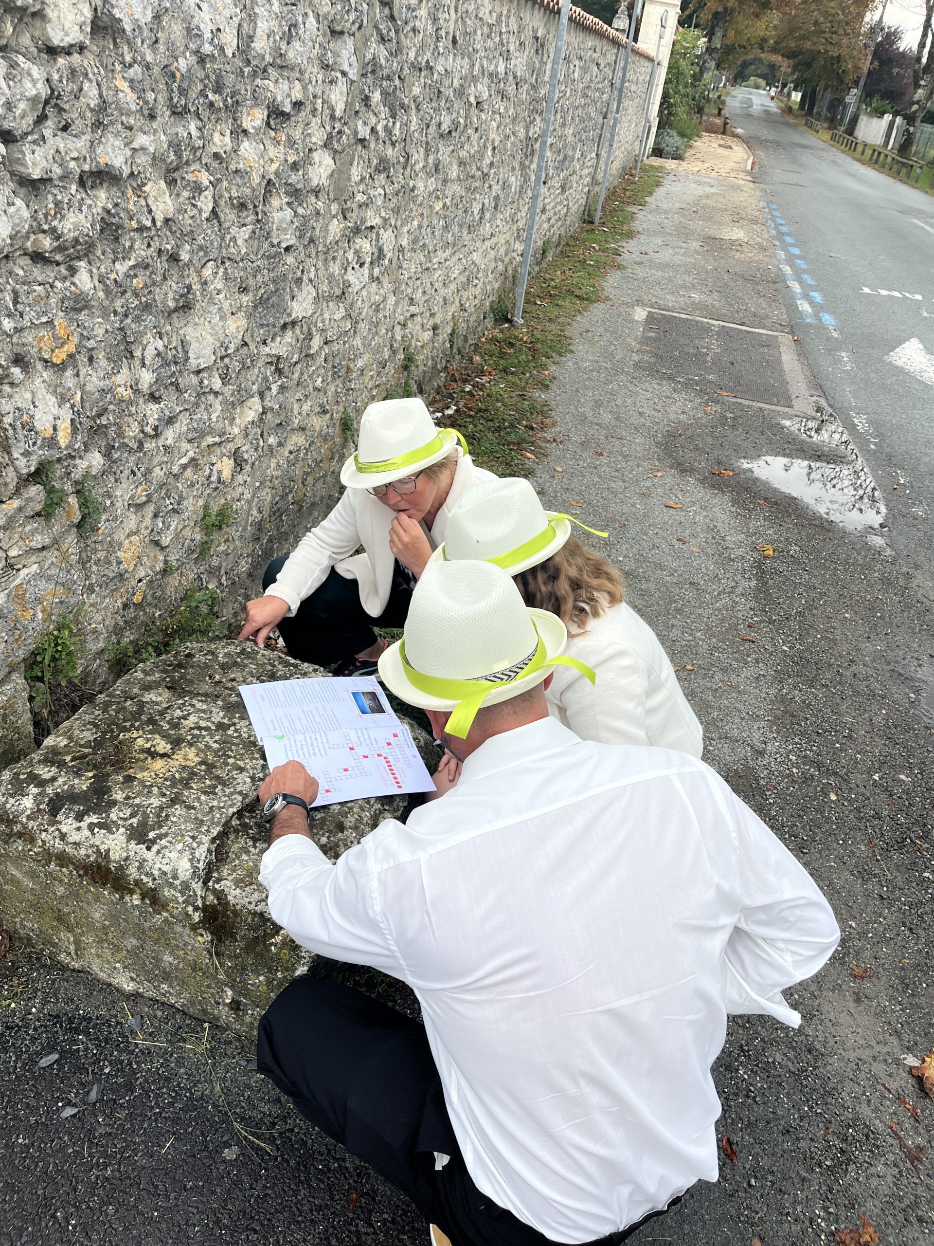 Équipe en chapeaux blancs penchée sur une carte d’indices lors d’une chasse aux trésors à Mornac-sur-Seudre